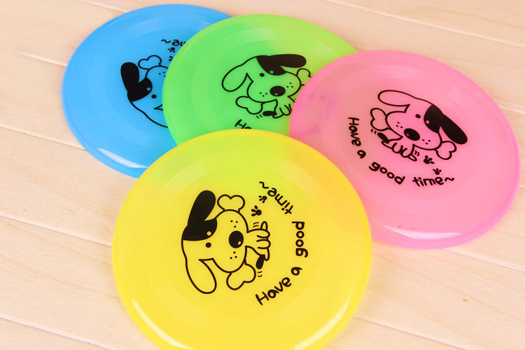 Four colorful frisbees with dog illustrations and text on a wooden surface