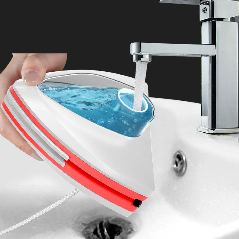 Hand holding a Magnetic Window Cleaner  with red accents under running water from a faucet.