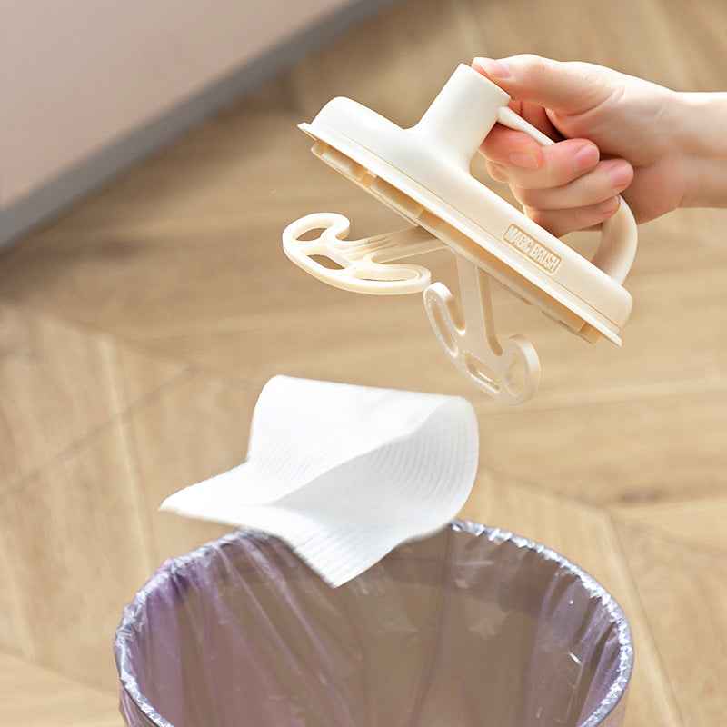 Hand using a white plastic bag holder to extract a white plastic bag from a clear trash bin on a wooden floor.